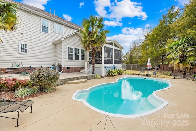 view of swimming pool with a sunroom and a patio area