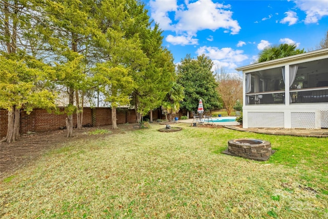 view of yard with an outdoor fire pit, a fenced in pool, and a sunroom