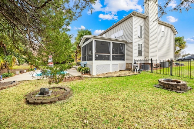 rear view of property featuring a sunroom, a fire pit, and a lawn