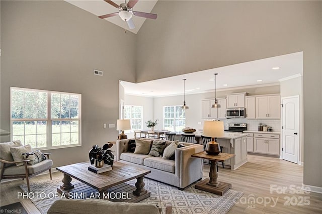 living room featuring light wood-type flooring, ceiling fan, and high vaulted ceiling