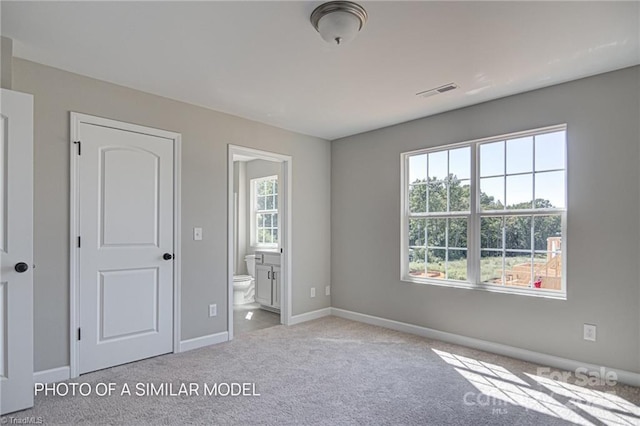 unfurnished bedroom featuring ensuite bathroom and light carpet