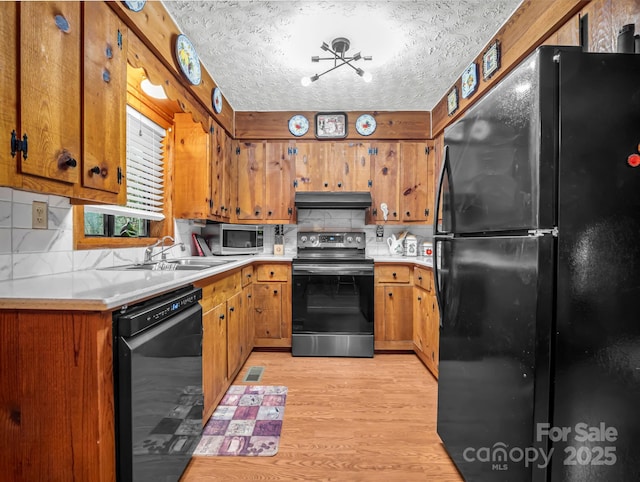 kitchen featuring a textured ceiling, light hardwood / wood-style floors, decorative backsplash, and black appliances