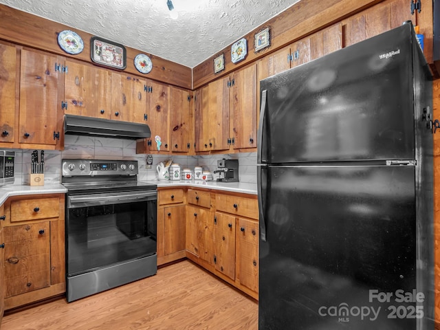 kitchen with tasteful backsplash, light wood-type flooring, a textured ceiling, and appliances with stainless steel finishes