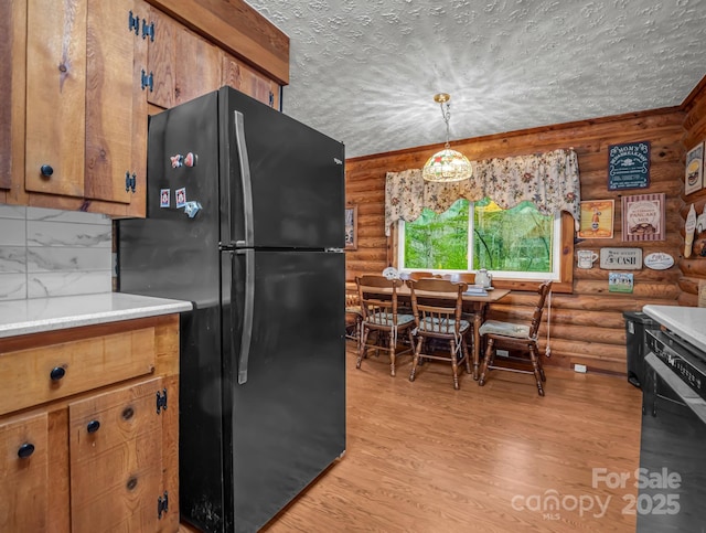 kitchen featuring black fridge, light hardwood / wood-style flooring, a textured ceiling, and decorative light fixtures