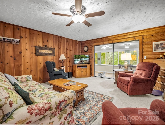 carpeted living room featuring ceiling fan, rustic walls, and a textured ceiling