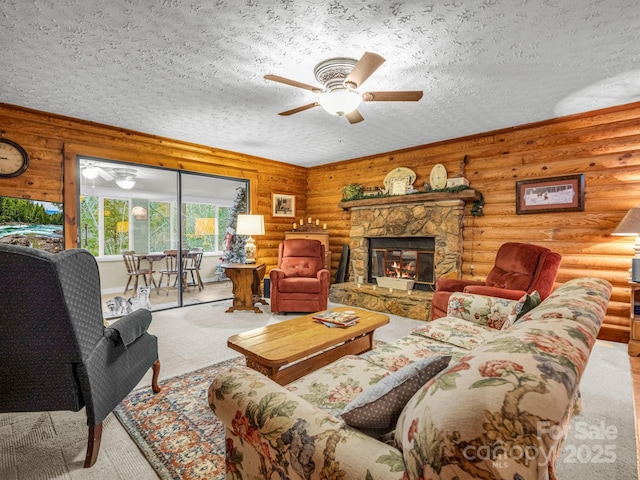 carpeted living room with ceiling fan, a stone fireplace, log walls, and a textured ceiling