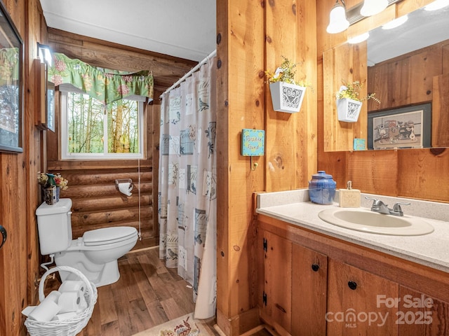 bathroom with walk in shower, toilet, vanity, hardwood / wood-style flooring, and log walls