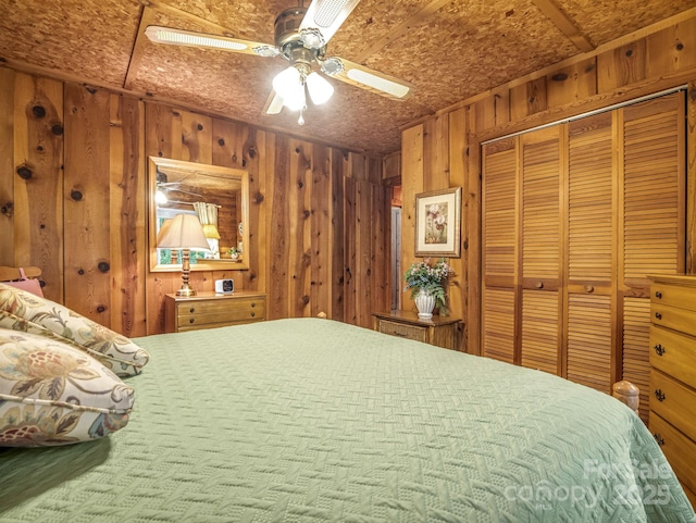 bedroom with a closet, ceiling fan, and wood walls