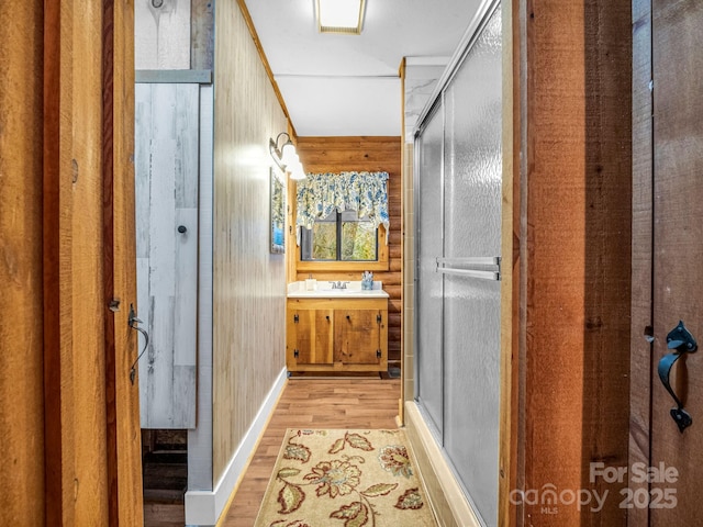 bathroom featuring vanity, hardwood / wood-style floors, wood walls, and walk in shower