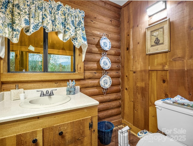 bathroom with vanity, rustic walls, and toilet