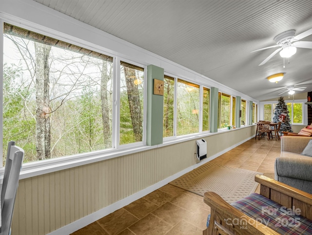 sunroom with heating unit, plenty of natural light, and ceiling fan