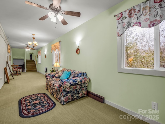 living room featuring ceiling fan with notable chandelier and carpet