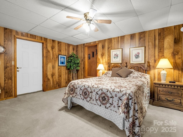 carpeted bedroom with ceiling fan and wooden walls