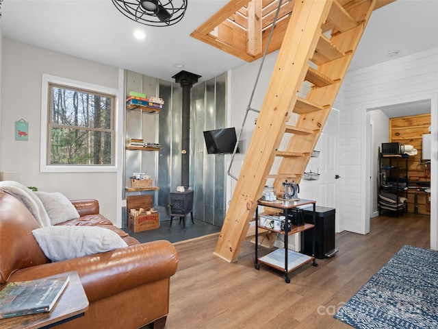 living area with hardwood / wood-style floors, wood walls, and a wood stove