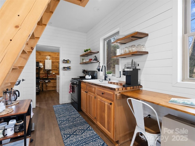 kitchen featuring dark hardwood / wood-style floors, black gas range oven, sink, and butcher block countertops