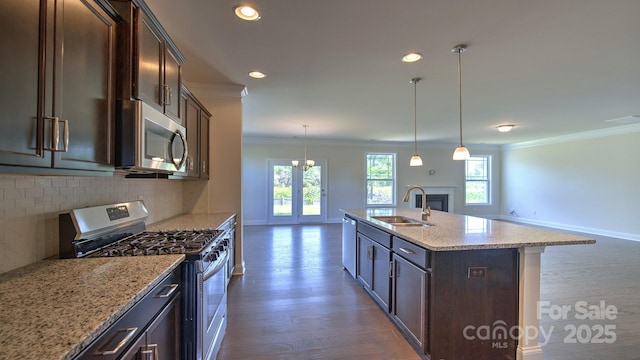 kitchen with stainless steel appliances, sink, tasteful backsplash, an island with sink, and pendant lighting