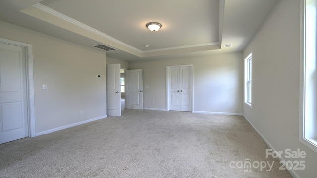 unfurnished bedroom with light carpet and a tray ceiling