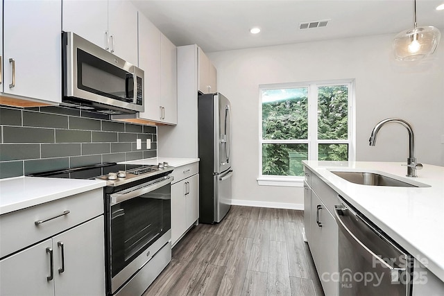 kitchen featuring sink, hanging light fixtures, appliances with stainless steel finishes, and white cabinets