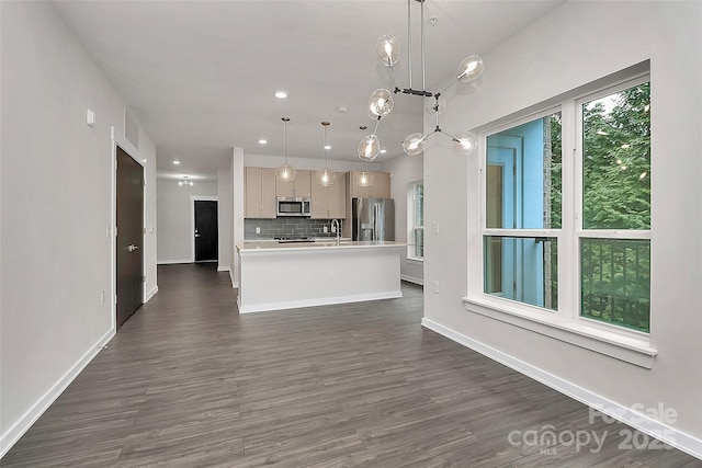 kitchen with stainless steel appliances, decorative backsplash, hanging light fixtures, dark hardwood / wood-style floors, and a kitchen island with sink