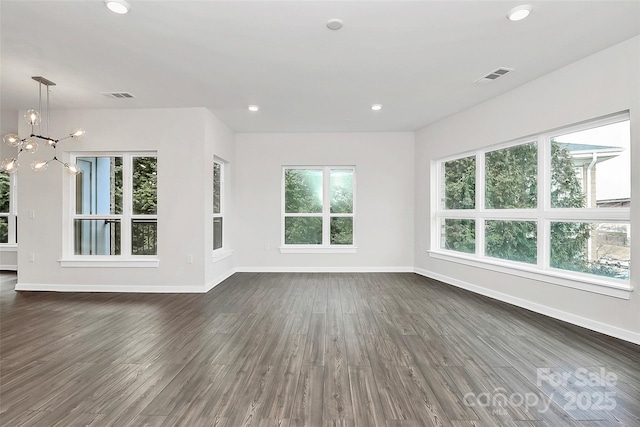 unfurnished living room featuring dark wood-type flooring and an inviting chandelier