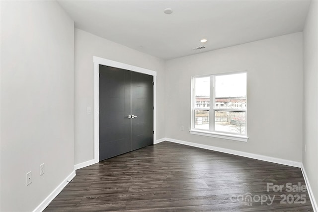 unfurnished bedroom featuring a closet and dark wood-type flooring