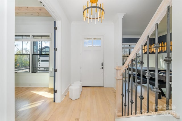 entryway featuring crown molding, a chandelier, and hardwood / wood-style flooring