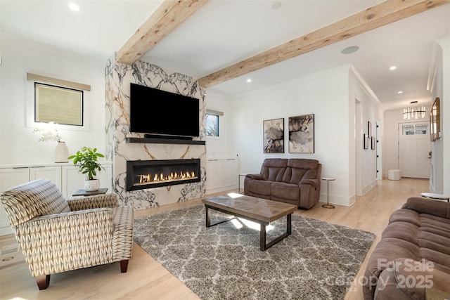 living room featuring light hardwood / wood-style flooring, ornamental molding, beamed ceiling, and a fireplace