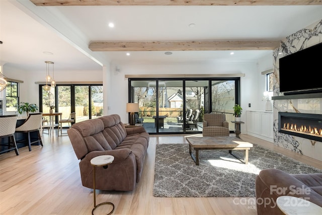 living room with french doors, a high end fireplace, beamed ceiling, and light hardwood / wood-style floors