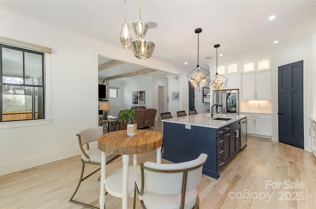 kitchen featuring hanging light fixtures, sink, white cabinetry, and light hardwood / wood-style flooring