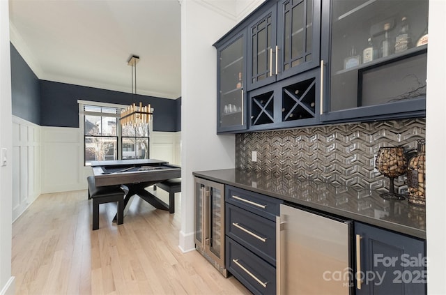 bar featuring decorative light fixtures, light hardwood / wood-style floors, beverage cooler, and tasteful backsplash