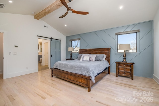 bedroom featuring ceiling fan, multiple windows, light hardwood / wood-style flooring, and a barn door