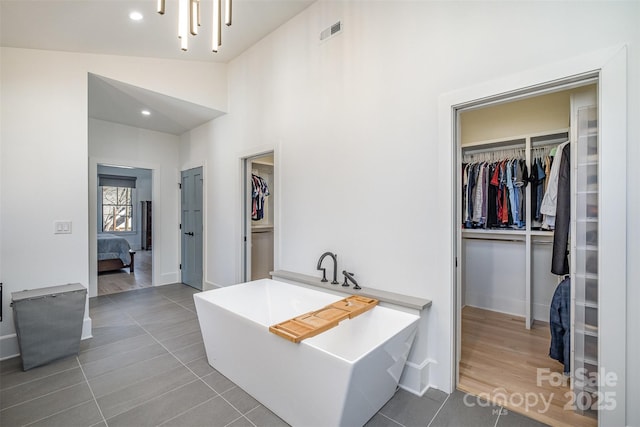 bathroom featuring vaulted ceiling, tile patterned flooring, and a tub