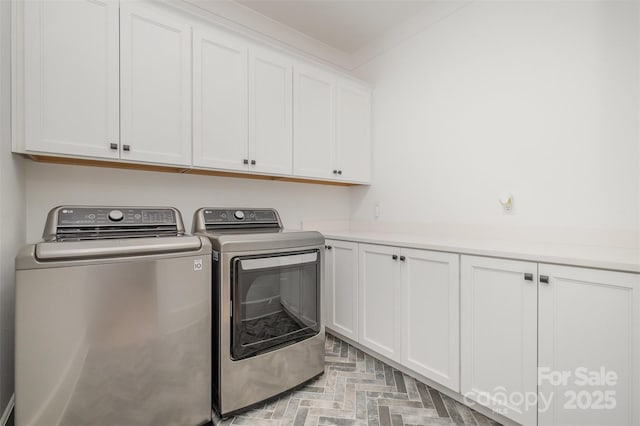 laundry area featuring washer and clothes dryer, ornamental molding, and cabinets