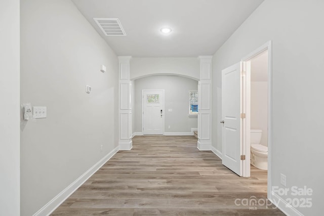 hall featuring ornate columns and light hardwood / wood-style floors