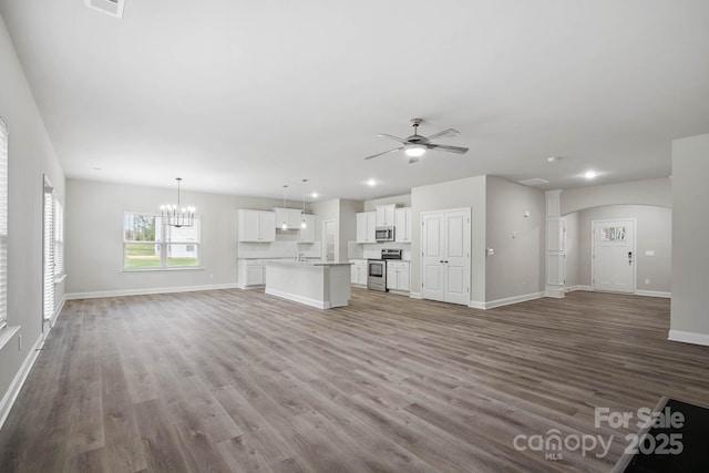 unfurnished living room with ceiling fan with notable chandelier, light wood-type flooring, and sink