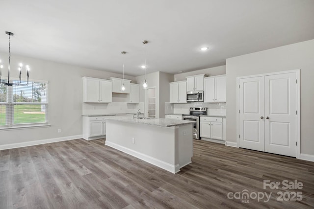 kitchen featuring sink, white cabinets, an island with sink, hanging light fixtures, and appliances with stainless steel finishes