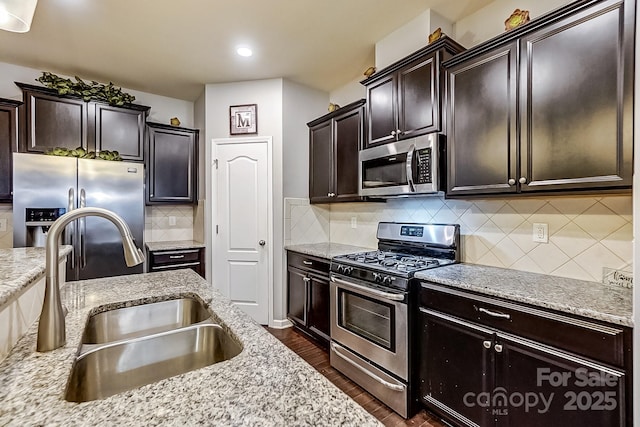 kitchen with stainless steel appliances, dark brown cabinets, backsplash, and sink