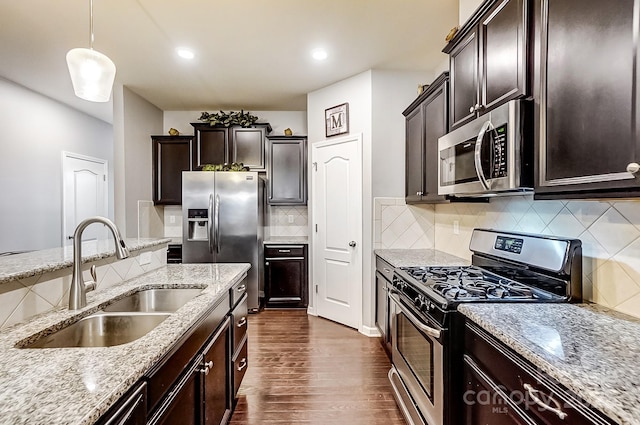 kitchen with appliances with stainless steel finishes, tasteful backsplash, dark hardwood / wood-style flooring, hanging light fixtures, and sink