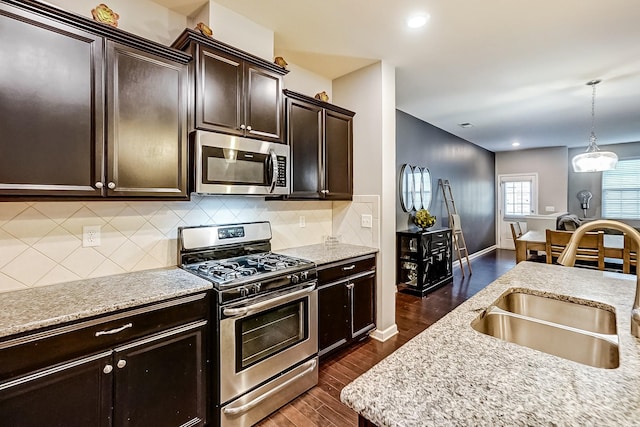 kitchen with stainless steel appliances, dark hardwood / wood-style floors, dark brown cabinets, pendant lighting, and sink