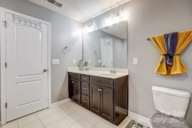 bathroom with toilet, vanity, and tile patterned flooring