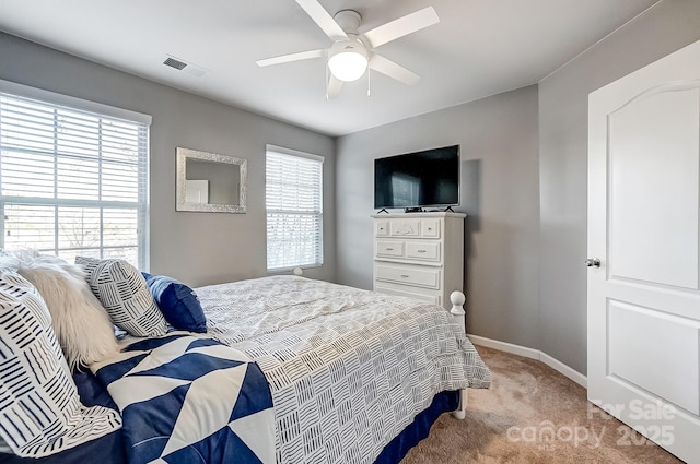 bedroom featuring light carpet, ceiling fan, and multiple windows