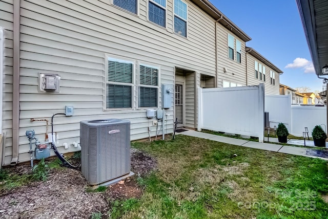 rear view of house featuring central AC and a yard