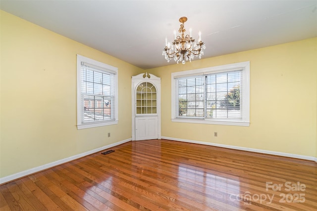 unfurnished dining area with an inviting chandelier and hardwood / wood-style flooring