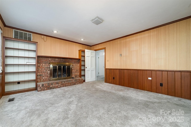 unfurnished living room with carpet floors, ornamental molding, a brick fireplace, and wooden walls