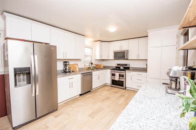 kitchen featuring light stone counters, decorative backsplash, white cabinets, and stainless steel appliances