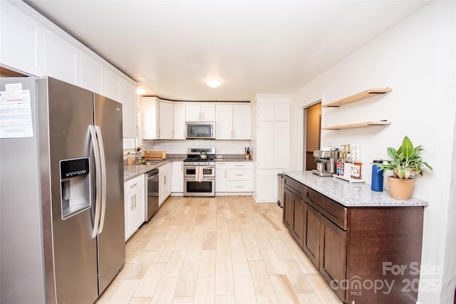 kitchen with appliances with stainless steel finishes, decorative backsplash, white cabinets, and sink