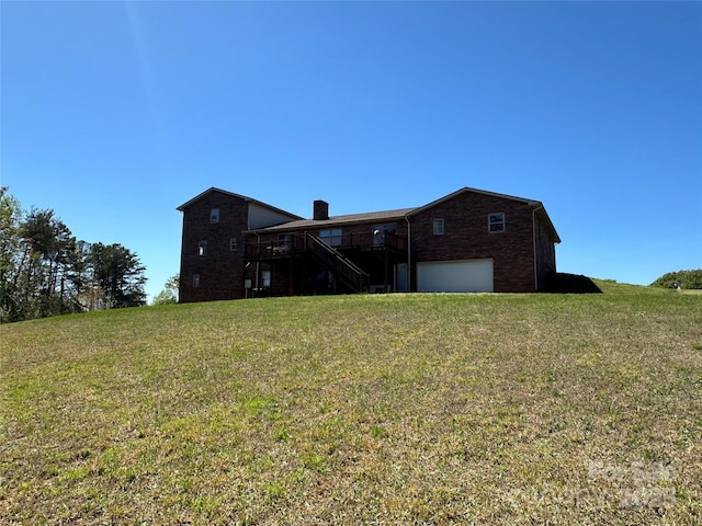 back of house featuring a yard, a garage, and a wooden deck