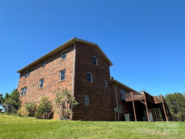 view of side of home featuring a wooden deck and a lawn