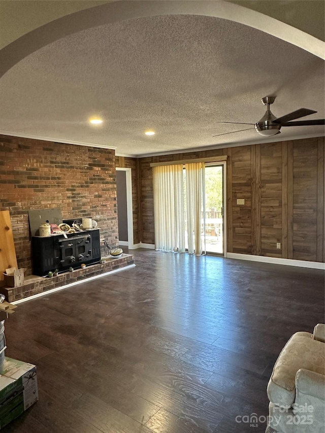 living room featuring a textured ceiling, wood walls, ceiling fan, and hardwood / wood-style floors