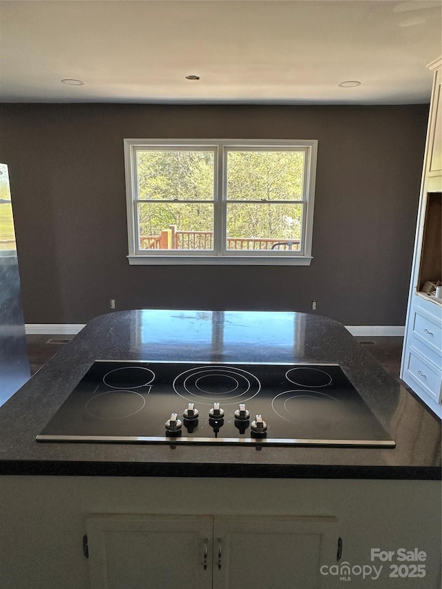 kitchen featuring white cabinets, black electric stovetop, and plenty of natural light